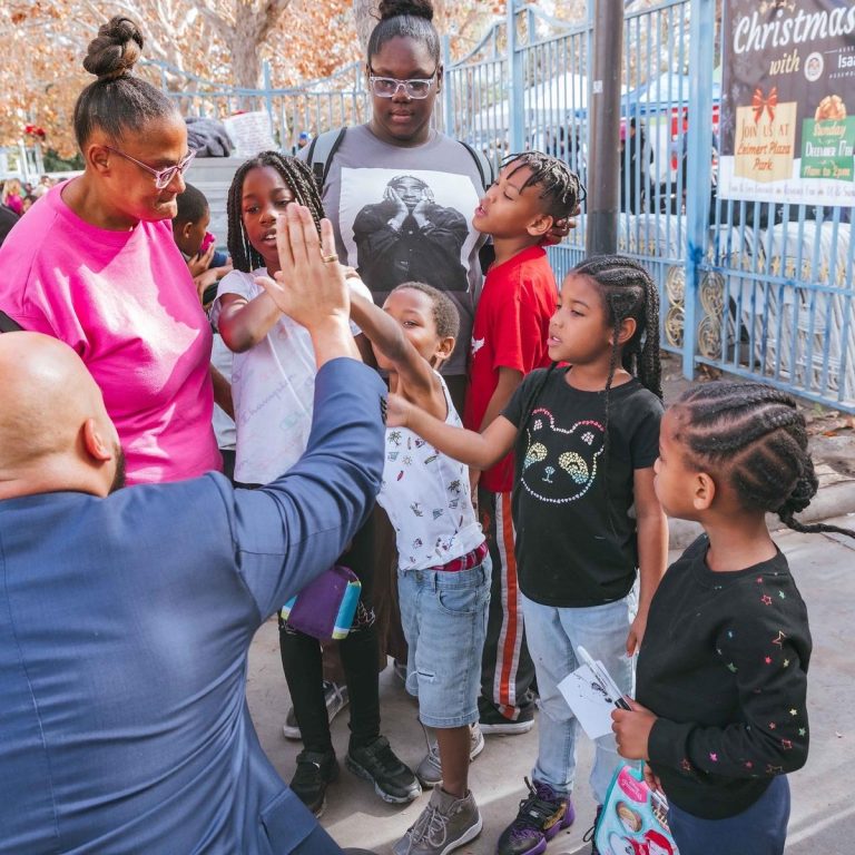 Isaac Bryan high-fiving children at a community holiday event