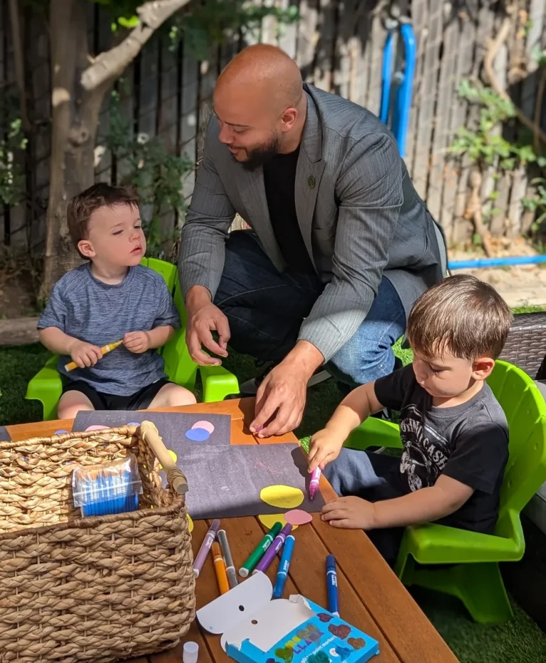 Isaac Bryan painting with young children at an outdoor activity table